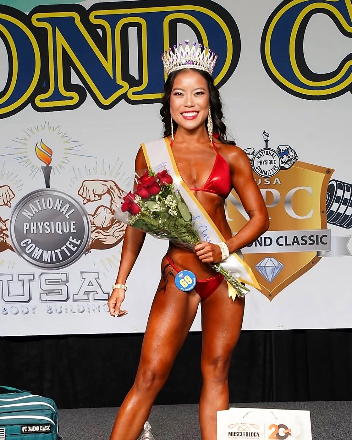 Posing client wearing a crown and holding flowers after a competition win